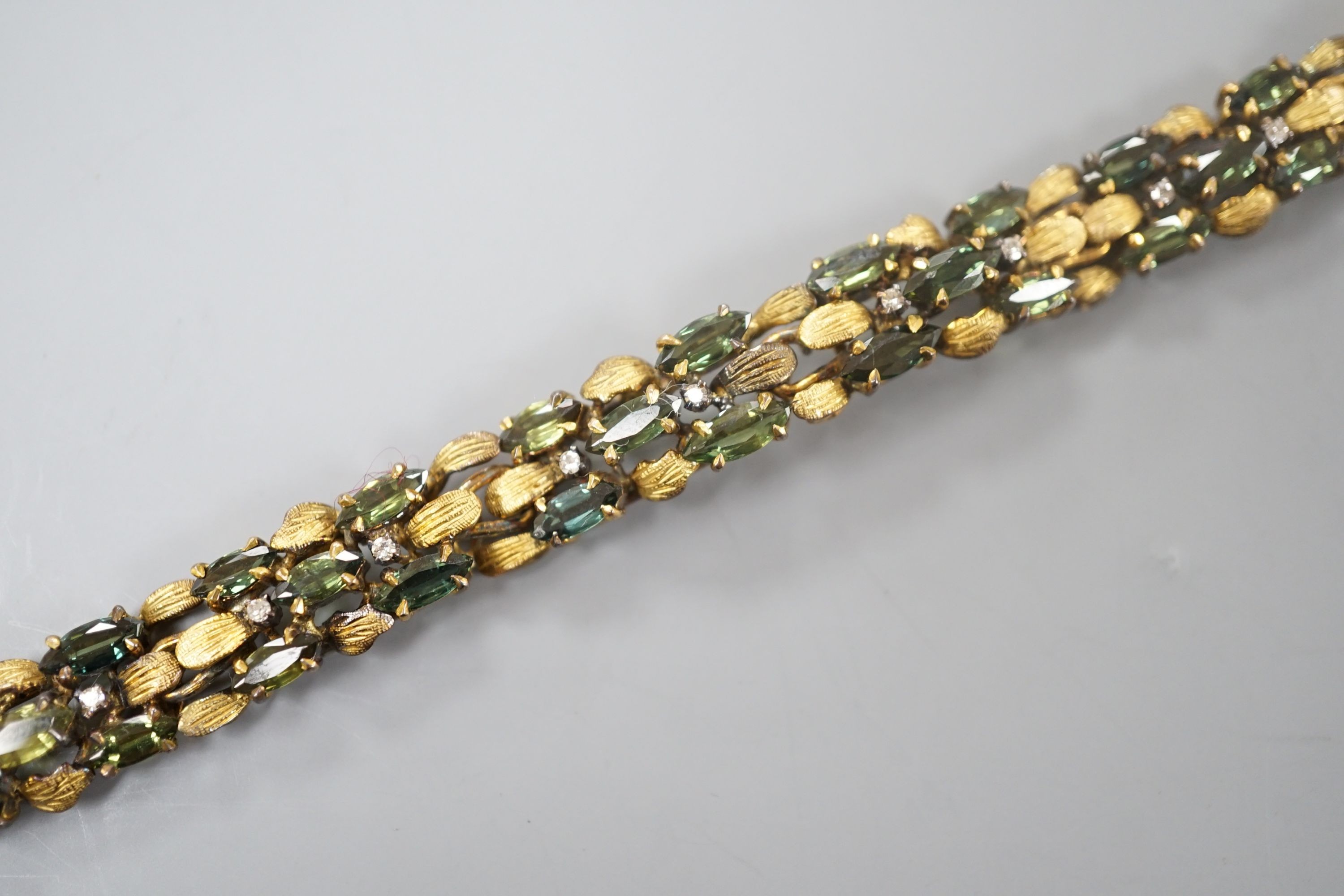 A modern yellow metal, multi green stone and multi diamond chip set bracelet, 16.5cm, gross weight 23.8 grams.